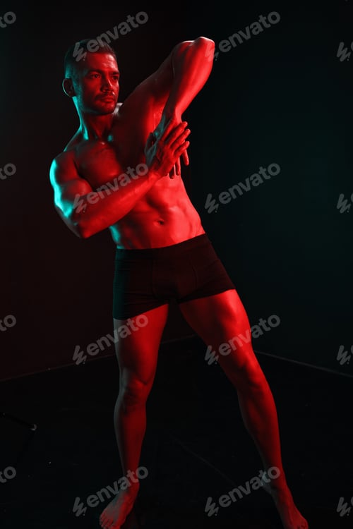 Preview: Man bodybuilder posing muscles with nude fitness torso, isolated on black background in neon light