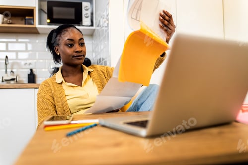 Preview: Young African American female student studying at home using laptop.