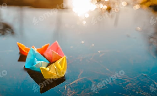 Preview: Multicolored paper boats. Colorful pink yellow blue orange ships in big spring snow puddle on