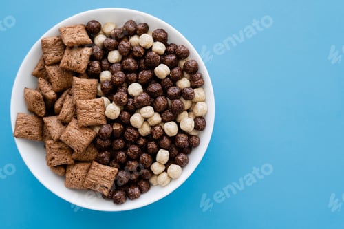 Preview: top view of bowl with tasty cereal balls and puffs isolated on blue