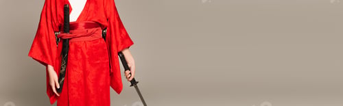 Preview: Cropped view of woman in oriental clothes holding sword isolated on grey, banner