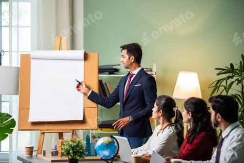 Preview: Group Of Businesspeople Looking At Young Indian asian Businessman Giving Presentation In Meeting