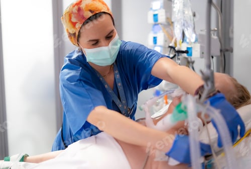 Preview: Nurse adjusting ventilator of patient in intensive care unit
