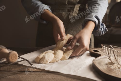Preview: Woman making braided bread at wooden table, closeup. Traditional Shabbat challah