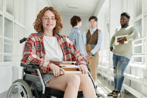 Preview: Smiling teenage girl in casualwear sitting in wheelchair in college corridor