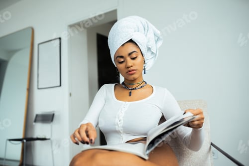 Preview: pretty african american woman with towel on head reading magazine at home