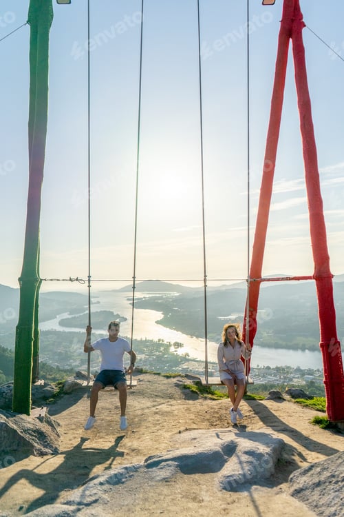 Preview: Young couple on a swing against a beautiful landscape