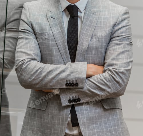 Preview: Mid-section of a professional businessman in an elegant suit and tie standing with his arms crossed