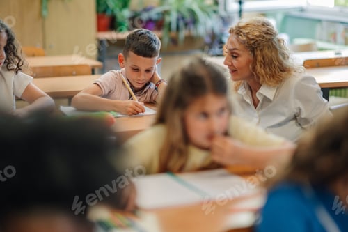 Preview: Teacher helping pupil during class in elementary school