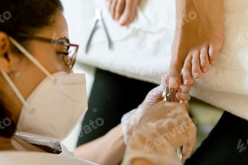 Preview: Beautician giving a pedicure painting her client's nails in a beauty centre