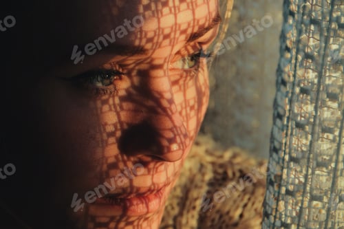 Preview: portrait of a woman standing next to a window, sunset through curtain cast a shadow on her face