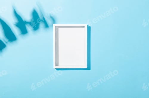 Preview: Blank white frame with shadow of leaves on blue background.