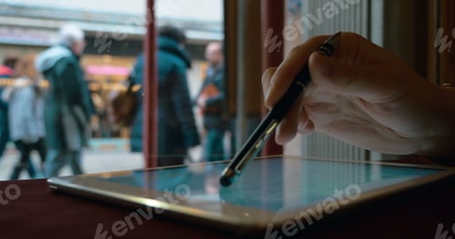 Preview: Woman working with touch pad by the window in cafe