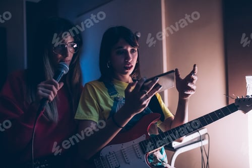 Vista previa: Mujeres guitarristas y cantantes que usan un teléfono inteligente