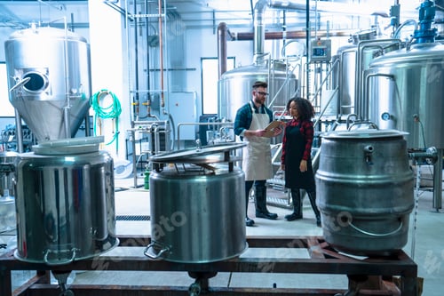 Preview: Colleagues in brewery standing looking at clipboard