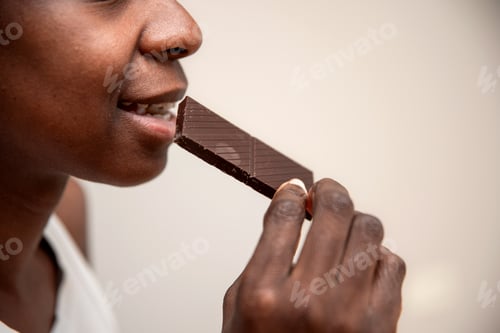 Preview: close up of african american woman Enjoying the bite of Dark Chocolate piece