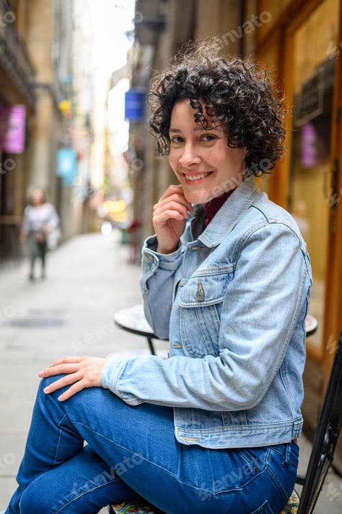 Preview: Smiling tourist sitting at outdoor cafe in Barcelona's gothic quarter