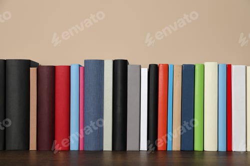 Preview: Many hardcover books on wooden table near beige wall