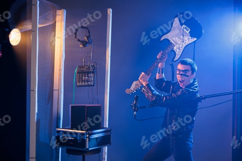 Preview: Ecstatic artist holding bass guitar to smash
