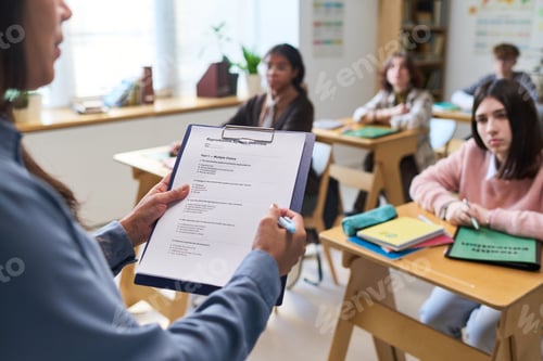Preview: Hispanic Teacher Holding Clipboard While Teaching Diverse Teenagers