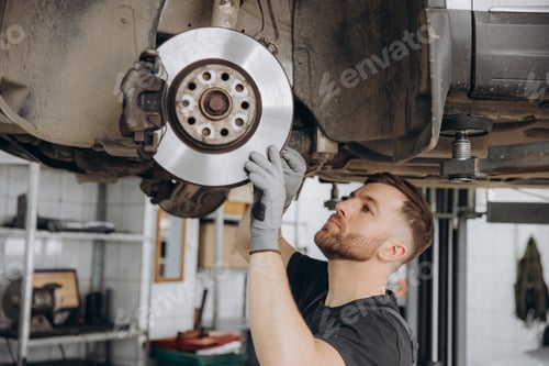 Preview: View from side of concentrated worker of car service checking running gear of automobile