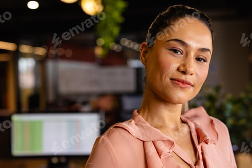 Preview: Business woman standing in open?plan office with data monitor, pendant lights and plant, copy space