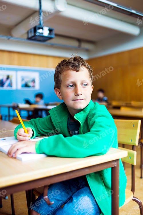 Estudante atencioso olhando para o outro lado enquanto está sentado à mesa na sala de aula