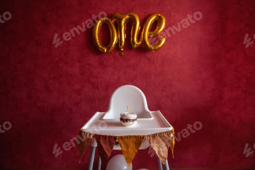 Preview: Festive birthday decorations. On red isolated wall, textured background foil gold letters ONE. Cake
