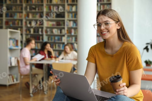 Preview: Young woman working on laptop in library. Space for text