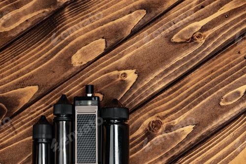 Preview: Vape and vape juice bottles on brown wooden background