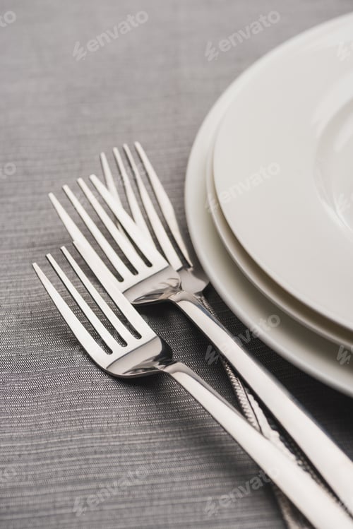 Preview: Shiny forks beside serving plates on grey tablecloth