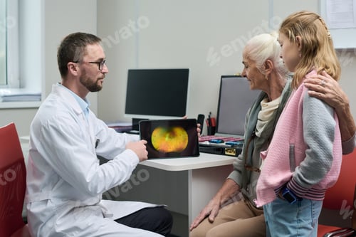 Preview: Senior Woman and Young Girl Observing Retinal Image with Doctor