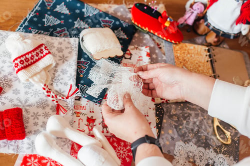 Preview: female hands make handmade dolls on the background of fabric, paper for scrapbooking, scissors