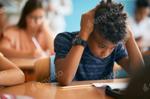 Preview: Uncertain African American schoolboy having exam during a class in the classroom.
