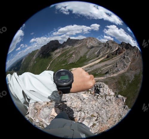 Preview: Hiker on high altitude mountain top checking the altimeter on the sports watch