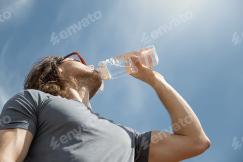 Preview: Brunette man drinking water in sunny day. Outdoors. Summer.