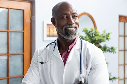 Preview: Happy african american male doctor wearing stethoscope and smiling at doctor's office