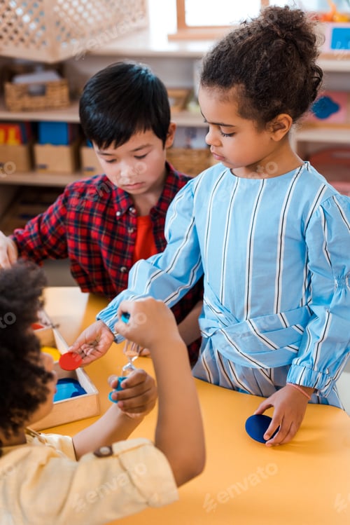 Preview: Selective focus of kids with hourglass and board game during lesson in montessori school