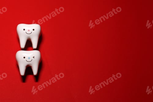 Preview: dental concept. two figurines of teeth on a red background. preparation for the dentist.