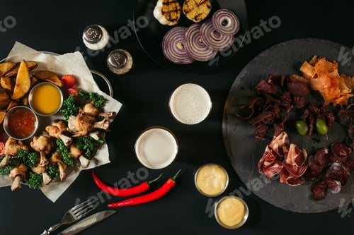 Preview: top view of glasses of beer, vegetables, baked potatoes with roasted chicken, various sauces and
