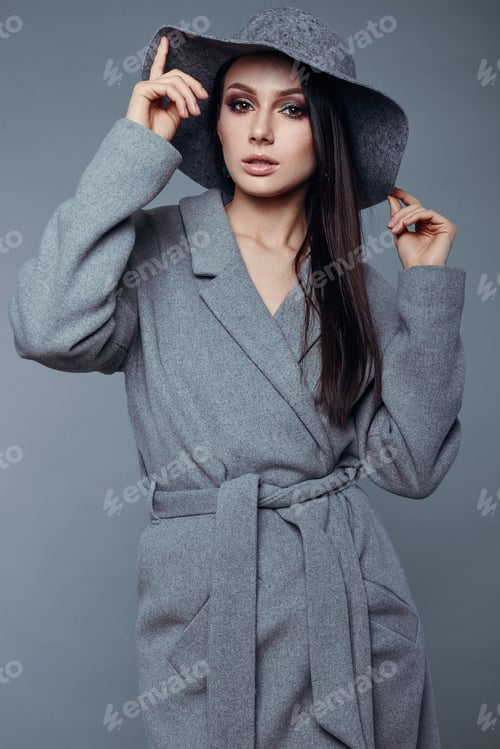 Preview: Young Fashion Brunette Woman Beauty Portrait Posing In Studio Wearing In Gray Coat And Hat