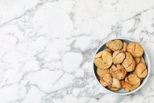 Preview: Bowl of dried figs on marble table, top view with space for text. Healthy fruit