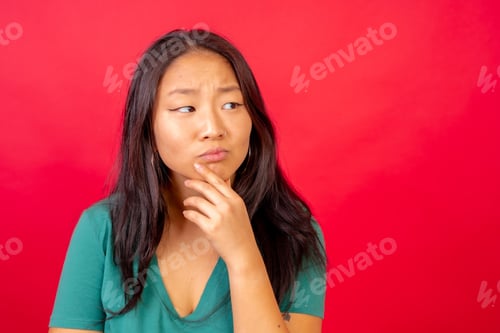 Preview: Curious and doubtful chinese woman with hand on chin