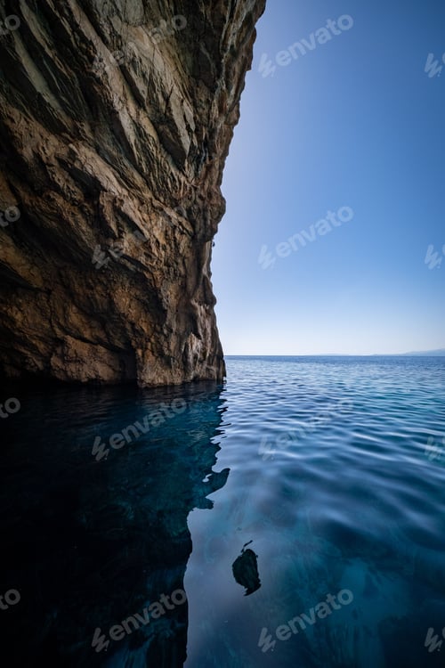Preview: Serene blue waters reflecting a coastal cliff under a clear sky in Zakynthos Island, Greece