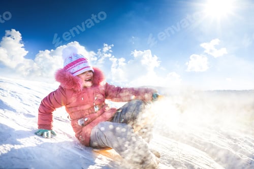 Preview: Happy girl sledding outdoors on clear winter day