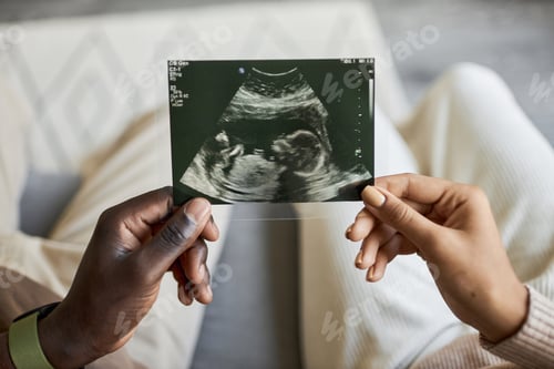 Preview: Close up of African American man and woman holding ultrasound picture together