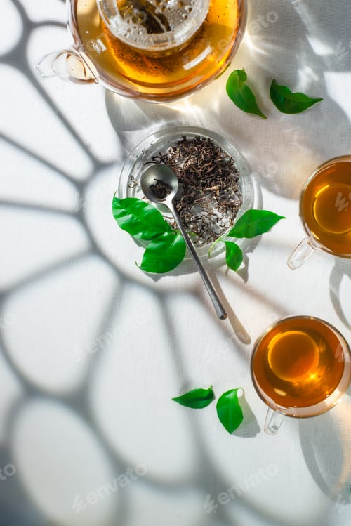Preview: Glass Teapot and Tea Cups on White Table