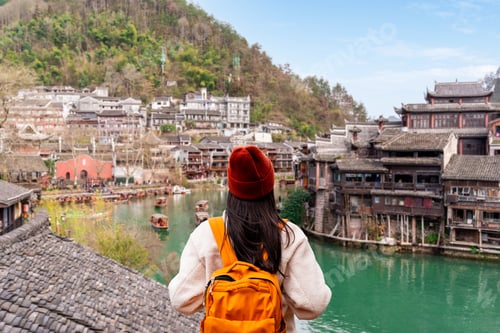 Preview: Young female tourist looking at the beautiful landscape at the Feng Huang Ancient Town