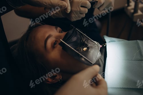 Preview: Dentistry at dentist. Young girl in protective glasses with open mouth.