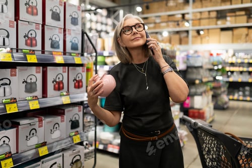 Preview: Woman shopping for kitchen appliances while talking on a smartphone at a retail store